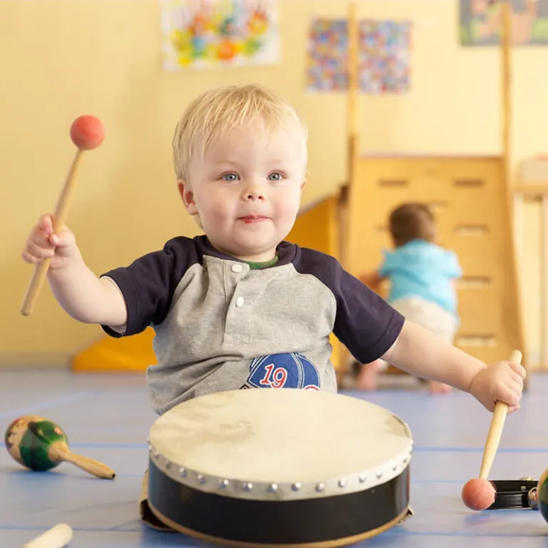 Child playing a drum with a mallet