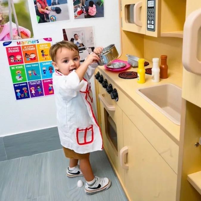 Child exploring a classroom play kitchen